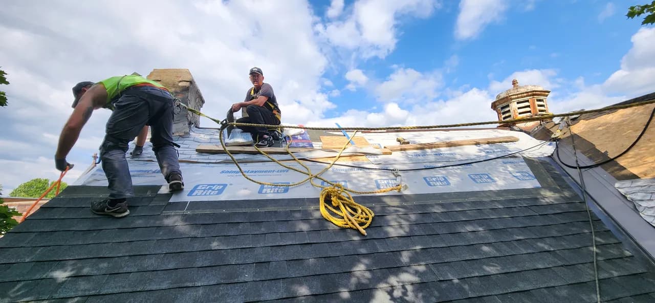 Crew working a tear-off and underlayment install on a roof ridge
