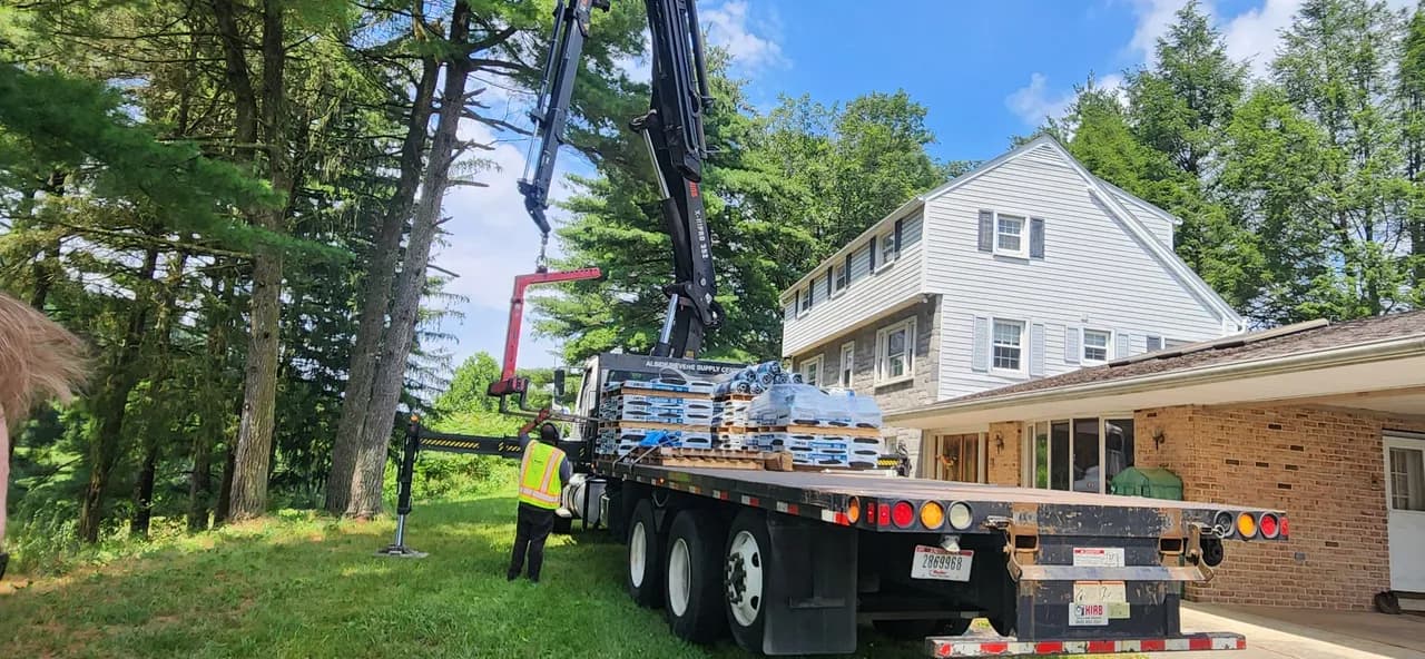 Boom truck delivering roofing materials to a homeowner's driveway