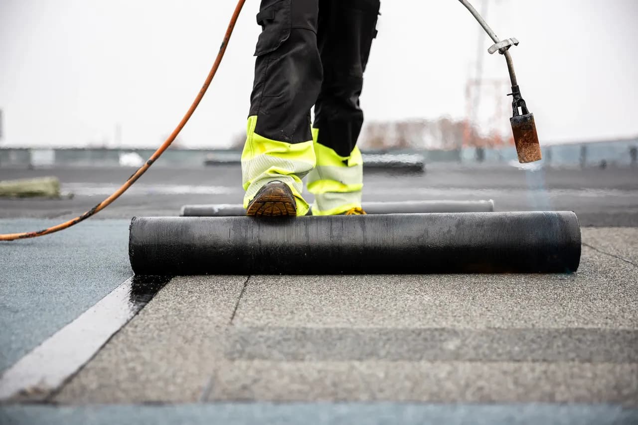 Technician installing torch-down membrane on a flat roof